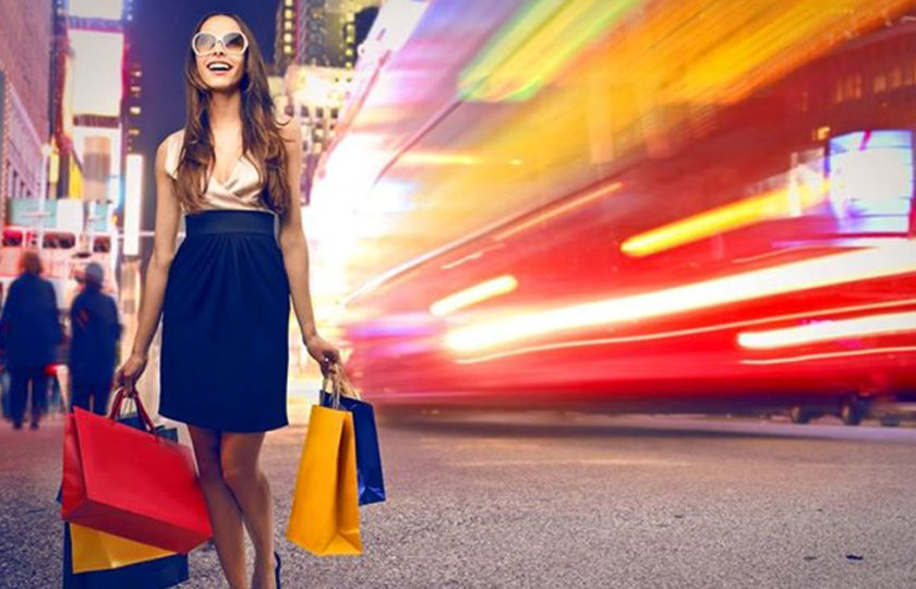 ragazza con borse shopping nelle mani passeggia per la città di sera